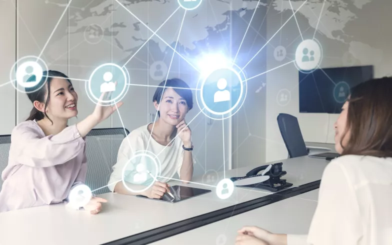 Frau am Konferenztisch tippt auf ein virtuelle Netzwerk